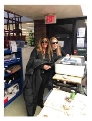 Kristin and Tina work on the Glowforge laser engraver (sunglasses required for safety).