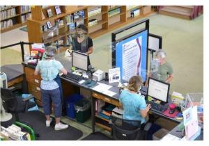 Library staff help patrons check out books at the circulation desk.